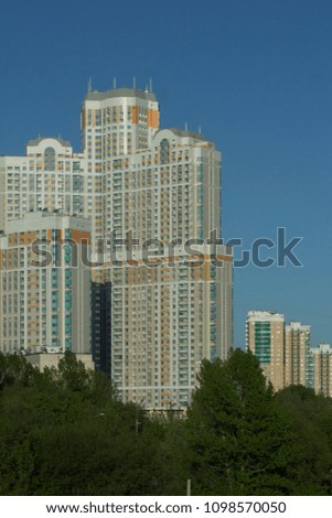 Very tall block of flats above the trees, blue sky background, Moscow, Russia