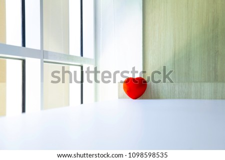 Red Heart on white table and light from a window. Romantic life concept.
