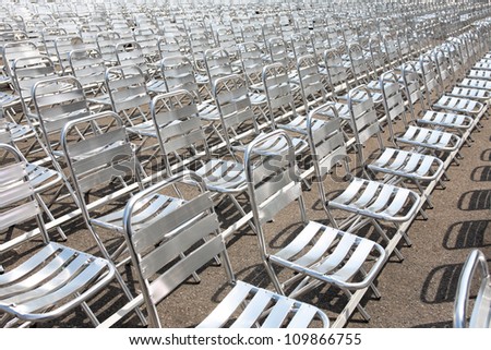 Lot of empty metal seats in a row outdoors under sun light