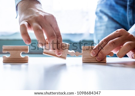 The man points to the same two incompatible jigsaw puzzles. The concept of misunderstanding, non-conforming elements, mutually exclusive statements. Royalty-Free Stock Photo #1098684347