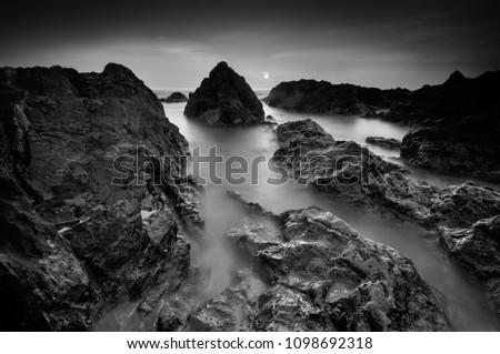 seascape rocky beach in black and white, A slow shutter speed was used to see the movement ( Soft focus due to long exposure shot )