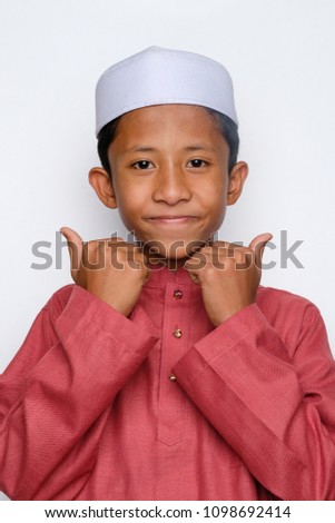 A young muslim malay boy wearing headgear called kopiah making good sign with his hand isolated on white background