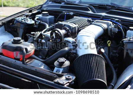 Under the hood of a sports car: a powerful gasoline engine with a supercharger and a small air filter. Royalty-Free Stock Photo #1098698510
