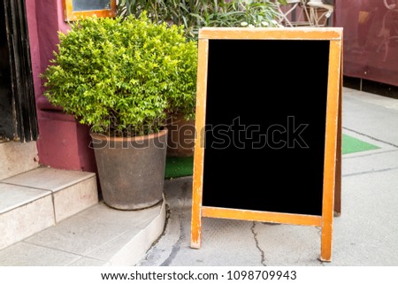 Wooden rustic blackboard in front of restaurant entrance