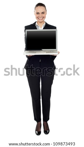 Full length portrait of attractive smiling woman presenting new laptop to you