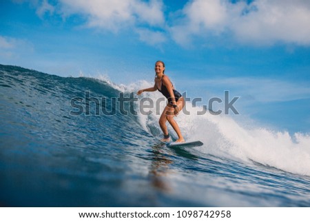 Surf woman at surfboard ride on wave. Woman in ocean during surfing. Surfer and ocean