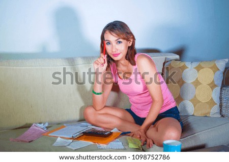young happy and satisfied latin woman accounting domestic finance expenses and income smiling using calculator checking payment receipts and bills at home living room couch in monthly balance
