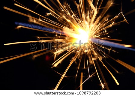Sparkler background / A sparkler is a type of hand-held firework that burns slowly while emitting colored flames, sparks, and other effects 
