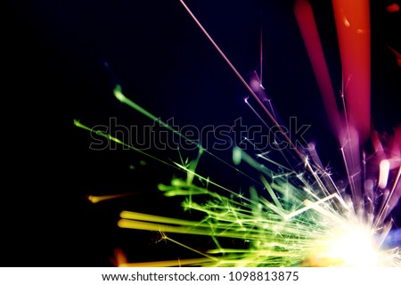 Sparkler background / A sparkler is a type of hand-held firework that burns slowly while emitting colored flames, sparks, and other effects 