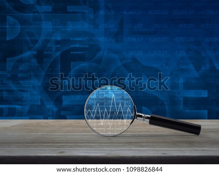 Magnifying glass with graph on wooden table over currency symbol with number, Business analyzing concept