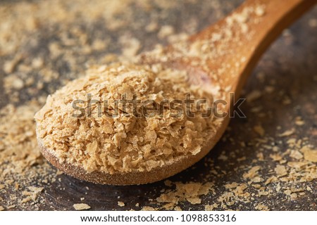 Closeup of nutritional brewers yeast flakes in wooden spoon Royalty-Free Stock Photo #1098853316