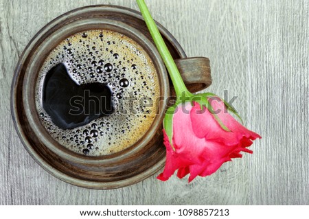 good morning. a cup of coffee and a red rose on a wooden table
