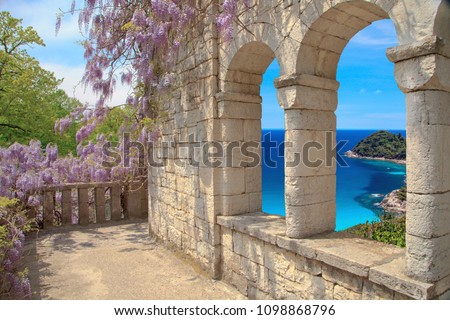 Beautiful view of the loggia and on the sea, a loggia of natural stone the masonry with arched windows ,  blossoming Wisteria on the loggia