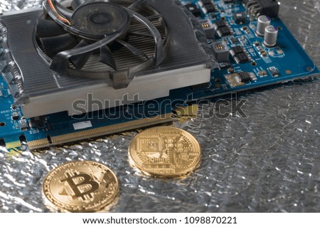 Bitcoin and video card, close-up. Cryptocurrency mining concept with golden bitcoins. Bitcoin mining farm device