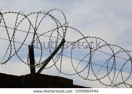 Red brick fence with barbed wire above. The concept of prison or private property