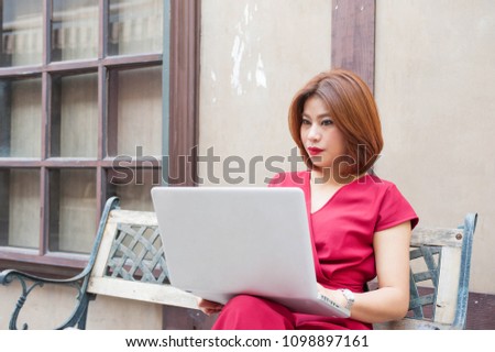 Red dress Asian women smile and enjoy with work in her laptop ,Red lips women