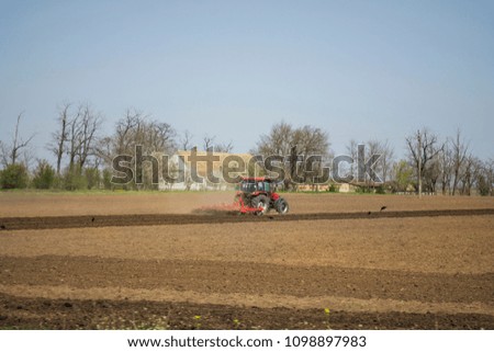 Farmer with tractor seeding - sowing crops at agricultural fields