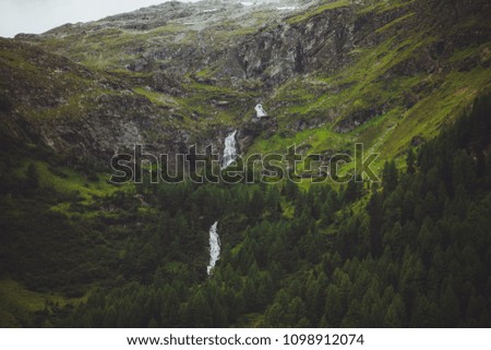 cascade of waterfalls in the mountains between green slopes with trees