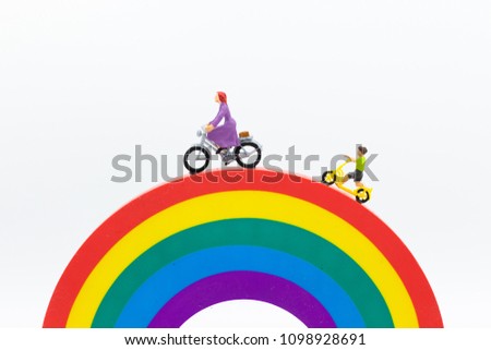 Miniature people : Mom and kids cycling on the rainbow. Image use for to be good model, family concept.