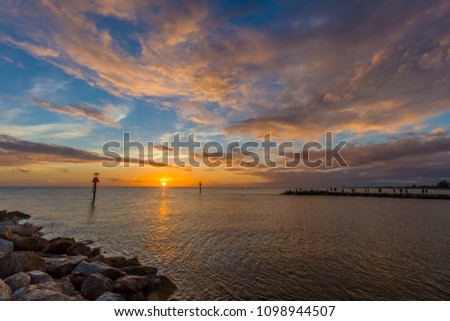 Colorful sunset over the Gulf of Mexico and the Gulf Intracoastal Waterway at the Venice Jetty in Venice Florida Royalty-Free Stock Photo #1098944507