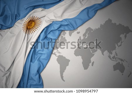 waving colorful national flag of argentina on a gray world map background.