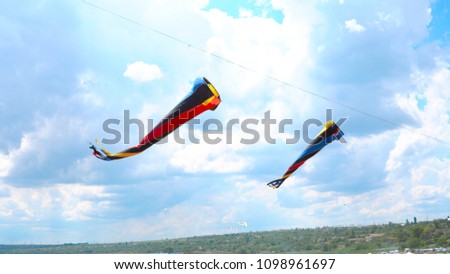 Multi-colored kites flying against the blue sky and clouds