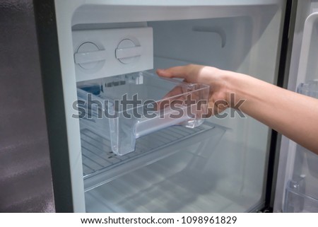 Woman hand open clear plastic ice container drawer in new refrigerator.