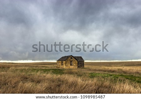 A Lone Abandoned House in the Western Prairie under Storm Clouds