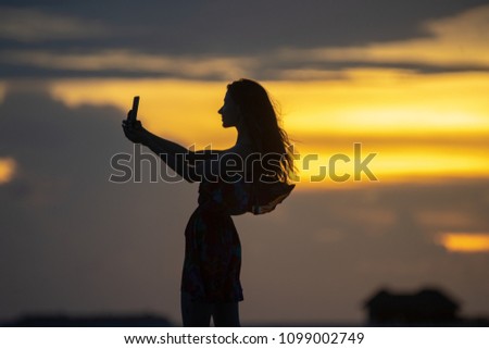 Girl on a sunset background makes a selfie