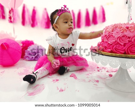 Little baby girl eating birthday cake during cake smash party