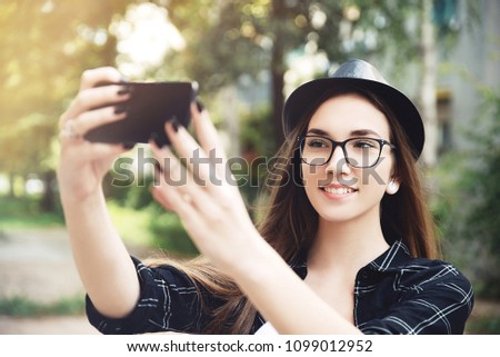 Young hipster woman with eyeglassses taking selfie in nature