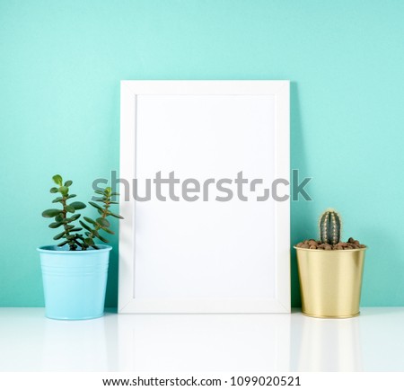 Blank white frame, plant cactus on white table against the blue 