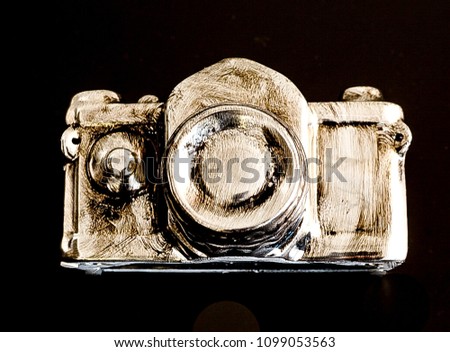 A modern version of a camera in silver and gold with black background