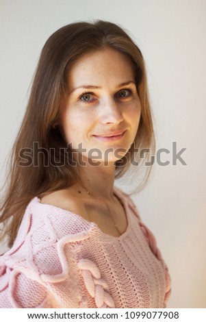 Cute green-eyed fair-haired girl in a rose sweater 