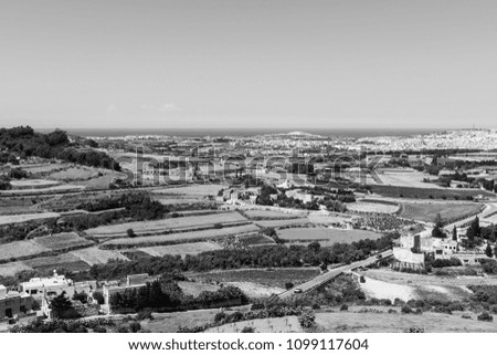 Rural landscape with asphalt roads and fields on Malta. Maltese city on the background of Mediterranean sea. Black and white picture