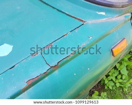Closeup picture of cracked and peeling paint on an old blue car.