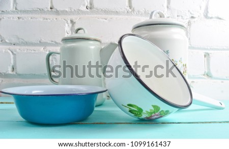 Lot of enameled dishes on a blue table against white brick wall background. Retro style cookware
