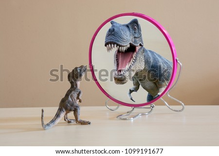 Little dinosaur with self confidence see a great dinosaur looking itself into the mirror  Royalty-Free Stock Photo #1099191677