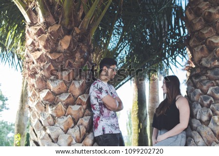 Boy leaning on palm tree with arms crossed