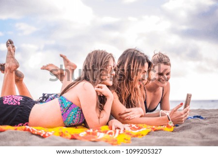 three nice and beautiful free girls at the beach lay down on the sand. vacation leisure outdoor activity under the sun taking selfiels with smartphone in friendship together. holiday young women