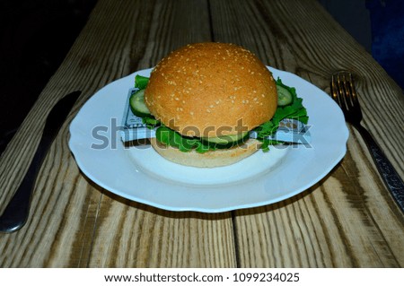 Hamburger with a bunch of dollars on a white plate