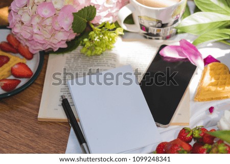 Studying languages, book, white sheet of paper, pen, cup with tea, phone, peonies on a wooden background