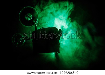 Old style movie projector, still-life, close-up. Film projector on a wooden background with dramatic lighting and selective focus. Movies and entertainment concept