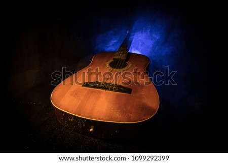 Music concept. Acoustic guitar on a dark background under beam of light with smoke. Guitar with Strings, close up. Selective focus. Fire effects.