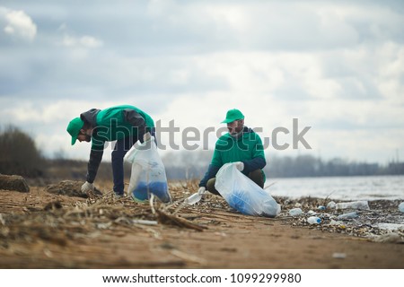 Ecology organization workers picking litter from dirty territory and utilizing it into special sacks Royalty-Free Stock Photo #1099299980