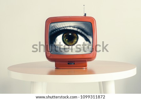 Female eye in an old retro TV screen. Creative concept. looking to the future  Royalty-Free Stock Photo #1099311872