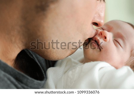 Father kissing his newborn baby girl. Close-up portrait