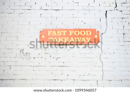 fast food takeaway sign on wall white brick background orange signage