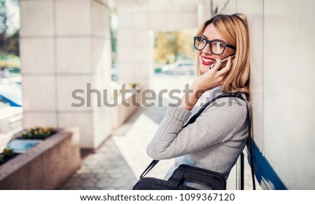 Young smiling businesswoman standing in front of the corporation and talking on a mobile phone. Business, education, lifestyle concept