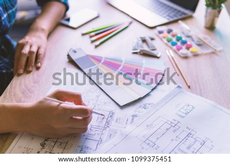 Interior designer designs make color on blueprint of house for present with customer.  engineering design at workplace concept.
